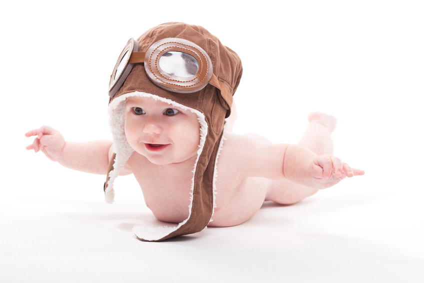 cute smiling baby in the cap of the pilot is flying on a white background. Photo with artistic blur and depth of field